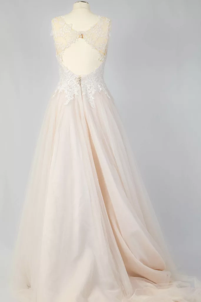 Secondhand-Brautkleid mit Spitzenoberteil und ausgestelltem Tüllrock in Pastellrosa auf Mannequin präsentiert