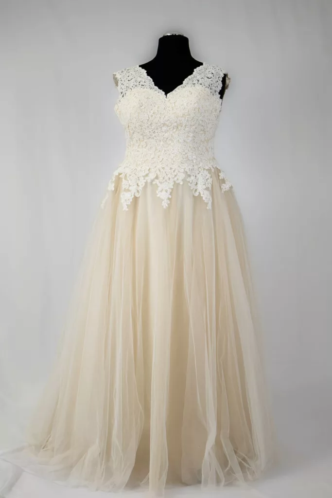 Elfenbeinfarbenes Brautkleid mit Spitzenoberteil und V-Ausschnitt auf einem Mannequin präsentiert